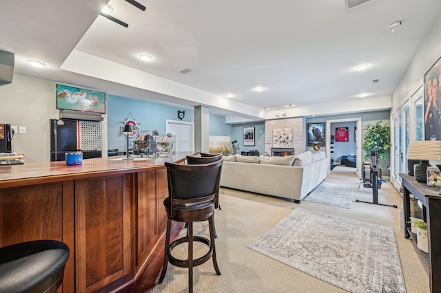 bar with light colored carpet and a fireplace