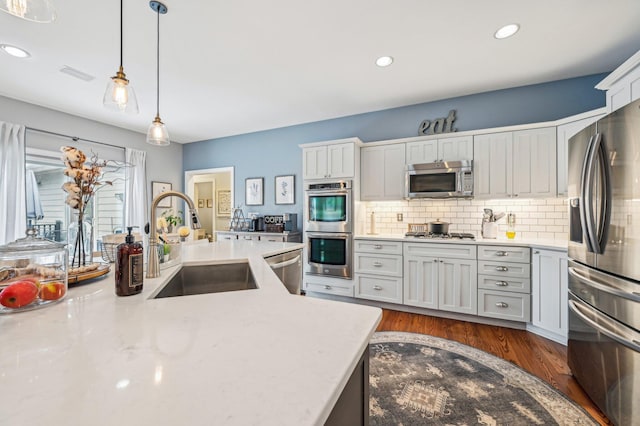 kitchen featuring sink, hanging light fixtures, dark hardwood / wood-style floors, stainless steel appliances, and decorative backsplash