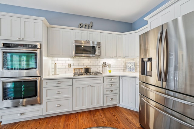 kitchen featuring white cabinetry, appliances with stainless steel finishes, light hardwood / wood-style flooring, and decorative backsplash