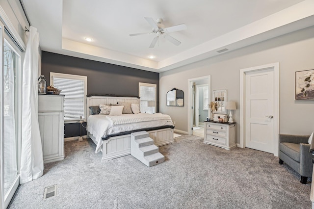 bedroom featuring ceiling fan, light colored carpet, and a raised ceiling