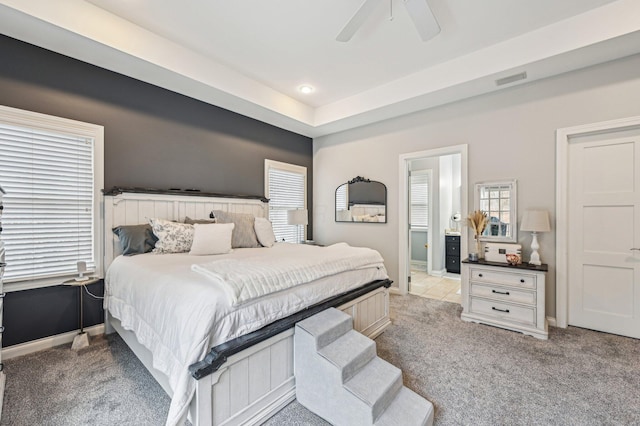 bedroom featuring connected bathroom, light colored carpet, and ceiling fan