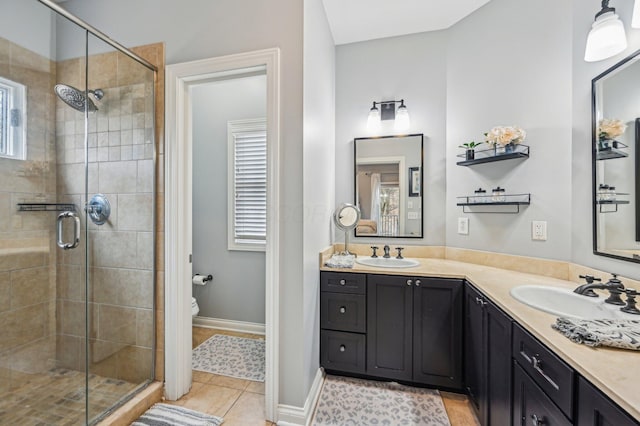 bathroom with vanity, a shower with shower door, tile patterned floors, and toilet