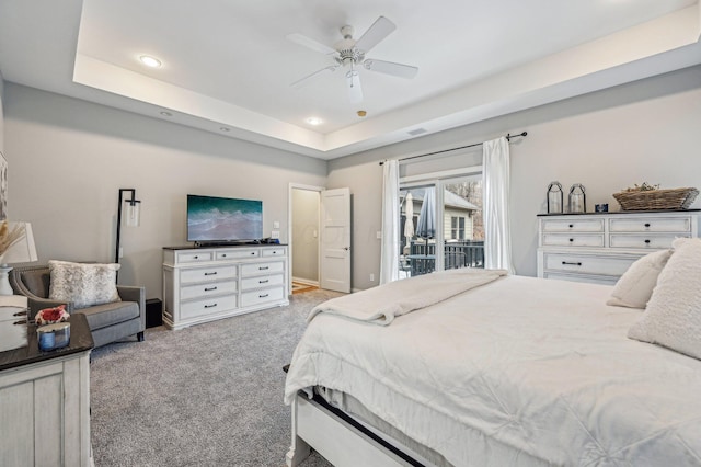 carpeted bedroom with a tray ceiling, access to outside, and ceiling fan