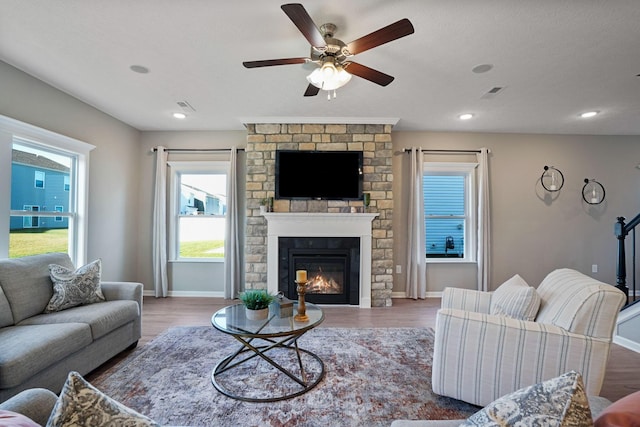 living room with ceiling fan, a large fireplace, and wood-type flooring