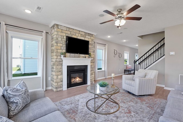 living room featuring ceiling fan, a fireplace, and wood-type flooring