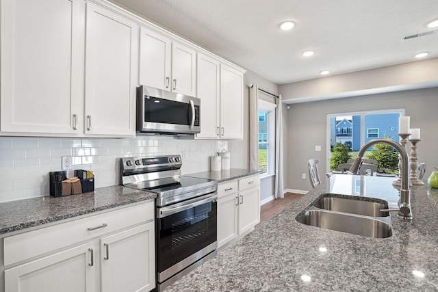 kitchen with white cabinetry, sink, stainless steel appliances, and dark stone counters