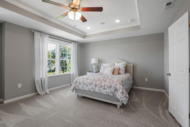 carpeted bedroom featuring crown molding, ceiling fan, and a raised ceiling