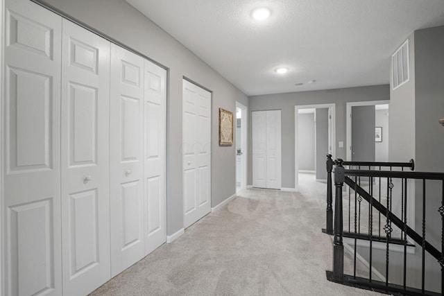 hall with light carpet and a textured ceiling