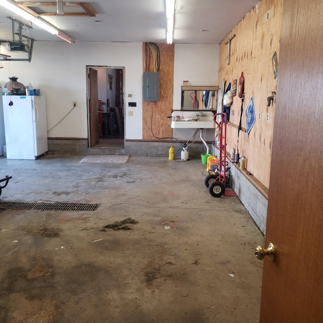 garage with a garage door opener, electric panel, and white refrigerator