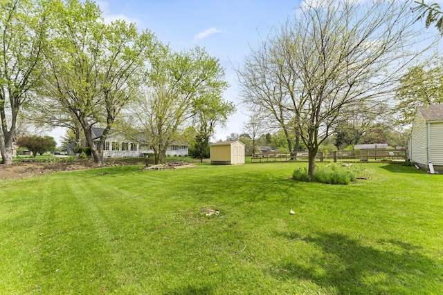 view of yard featuring a storage unit, an outdoor structure, and fence
