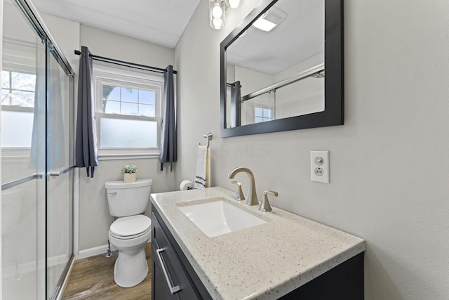 full bath with a stall shower, wood finished floors, vanity, baseboards, and toilet