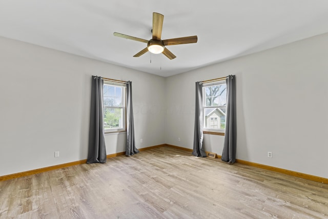 empty room featuring plenty of natural light, a ceiling fan, and light wood-type flooring