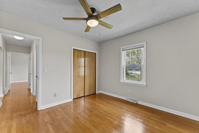 unfurnished bedroom featuring baseboards, a closet, light wood-type flooring, and visible vents