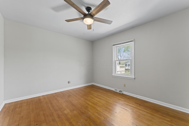 unfurnished room featuring baseboards, hardwood / wood-style floors, and visible vents