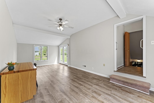 unfurnished living room with a ceiling fan, baseboards, lofted ceiling with beams, and wood finished floors
