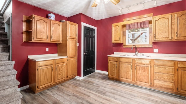 kitchen with sink, ceiling fan, and light wood-type flooring