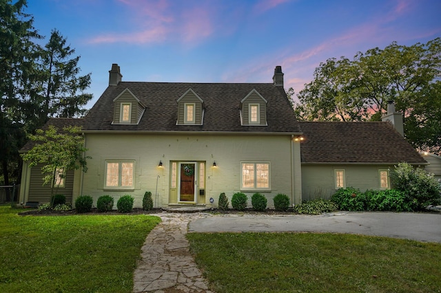 cape cod house featuring a lawn