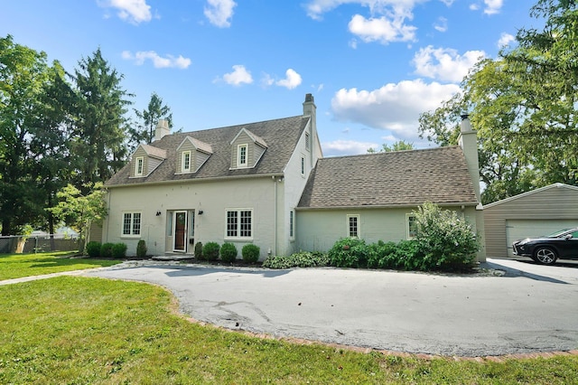 cape cod-style house featuring a garage, an outbuilding, and a front yard