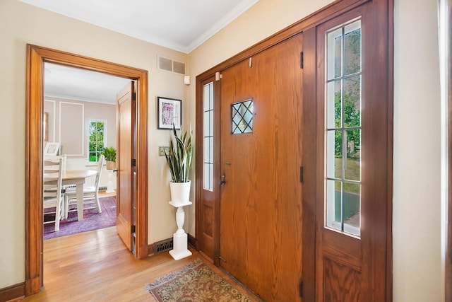 foyer entrance with ornamental molding and light wood-type flooring