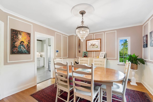 dining space featuring ornamental molding, a chandelier, and light wood-type flooring