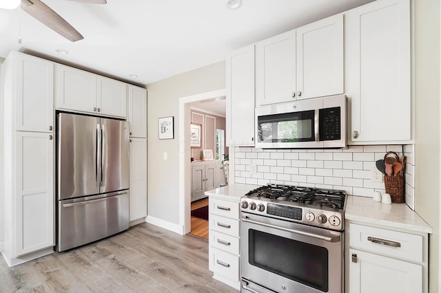 kitchen featuring tasteful backsplash, appliances with stainless steel finishes, light hardwood / wood-style flooring, and white cabinets