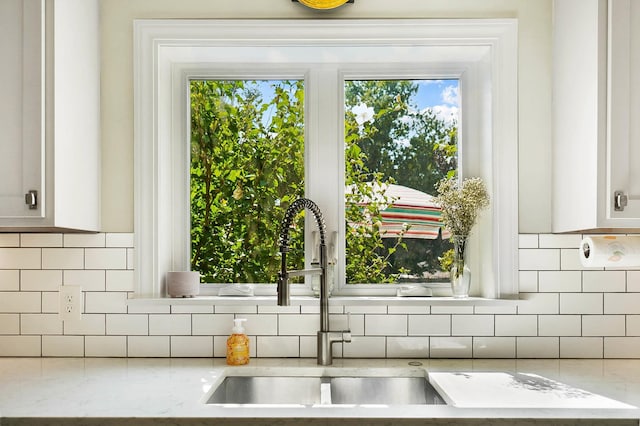 room details featuring white cabinetry, light stone countertops, and backsplash