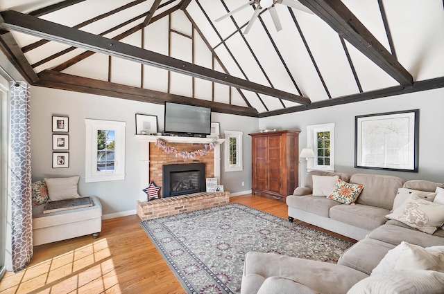 living room with a fireplace, beam ceiling, plenty of natural light, and light wood-type flooring