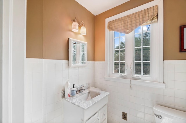 bathroom with vanity, tile walls, and toilet