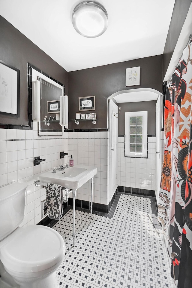 bathroom with tile walls, toilet, and a shower with shower curtain