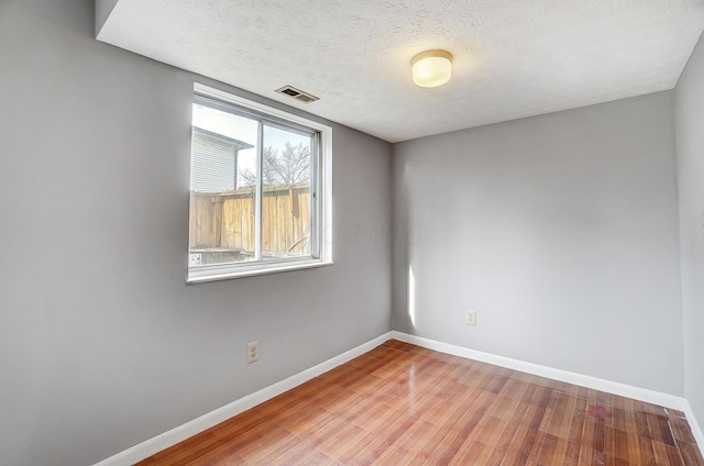 unfurnished room featuring light hardwood / wood-style flooring and a textured ceiling