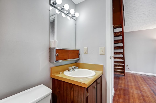 bathroom with hardwood / wood-style flooring, vanity, a textured ceiling, and toilet