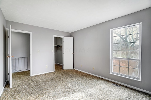 unfurnished bedroom featuring a walk in closet, carpet, and a closet