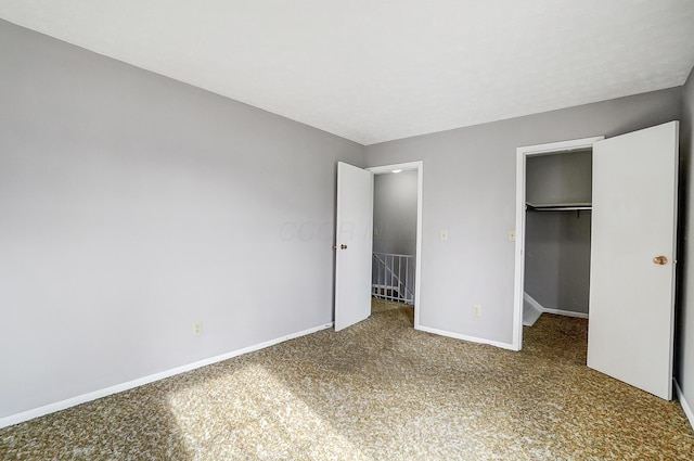 unfurnished bedroom with carpet flooring, a closet, and a spacious closet