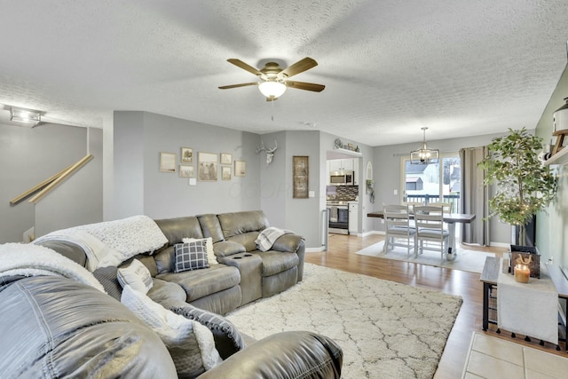 living room with a textured ceiling, light hardwood / wood-style flooring, and ceiling fan