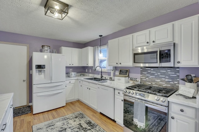 kitchen with sink, stainless steel appliances, light hardwood / wood-style floors, white cabinets, and decorative light fixtures