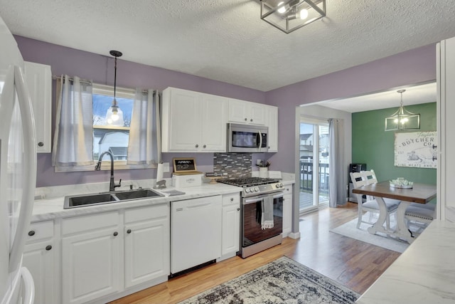 kitchen with white cabinetry, sink, pendant lighting, and stainless steel appliances