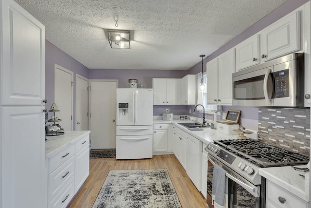 kitchen featuring hanging light fixtures, appliances with stainless steel finishes, sink, and light hardwood / wood-style flooring