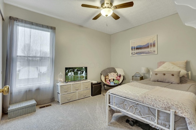 carpeted bedroom with ceiling fan and a textured ceiling