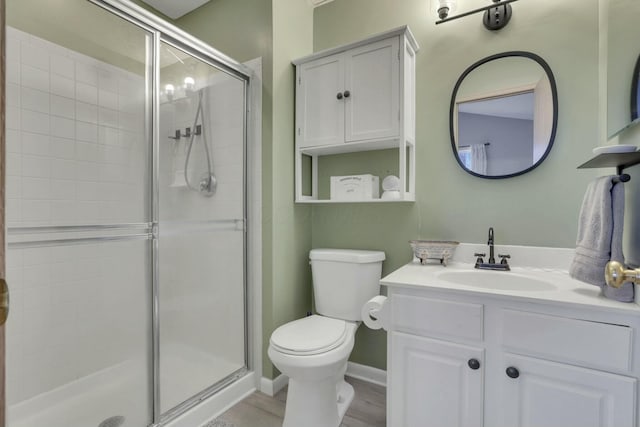 bathroom with vanity, wood-type flooring, a shower with shower door, and toilet