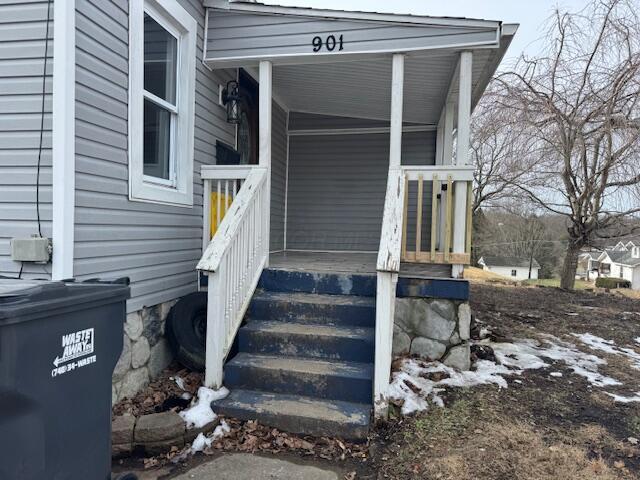 snow covered property entrance with covered porch