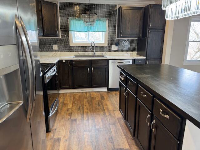 kitchen featuring pendant lighting, sink, backsplash, stainless steel appliances, and dark wood-type flooring