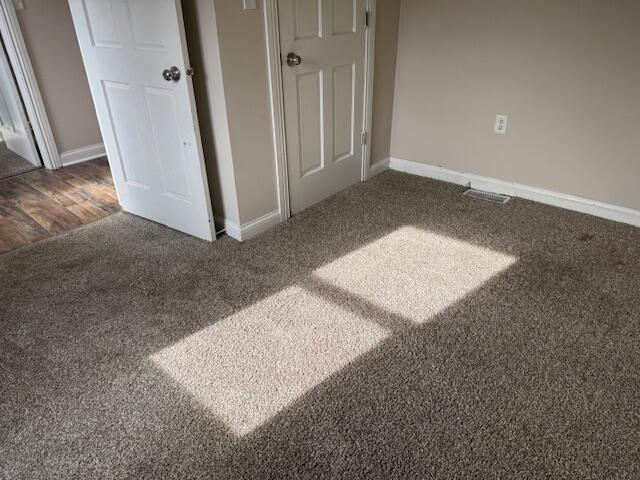 unfurnished bedroom with dark carpet