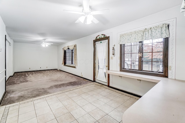 foyer entrance with ceiling fan and light carpet