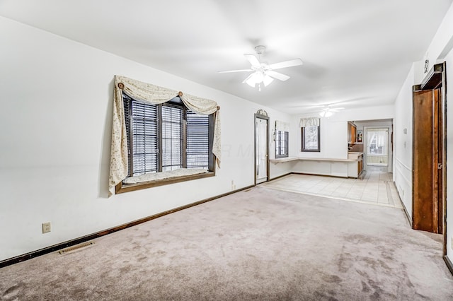 unfurnished living room with plenty of natural light, light carpet, and ceiling fan