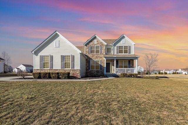 view of front of house with stone siding, covered porch, and a front lawn