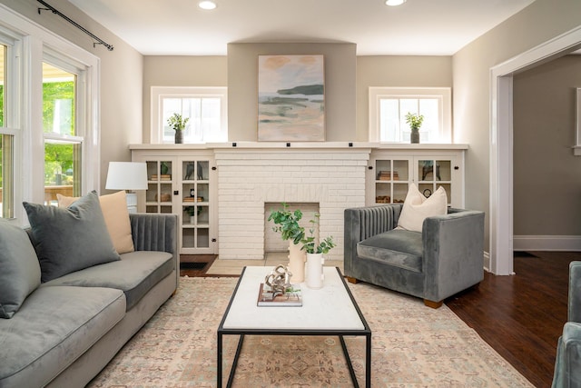 living room with wood-type flooring and a brick fireplace