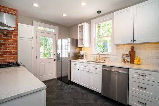 kitchen featuring sink, appliances with stainless steel finishes, light stone counters, white cabinets, and decorative light fixtures