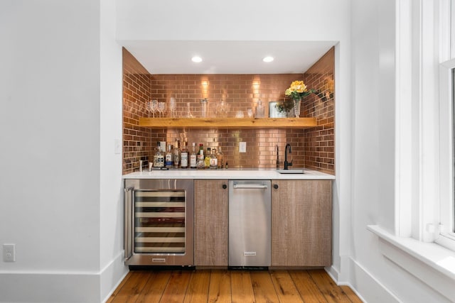 bar with sink, hardwood / wood-style floors, and beverage cooler