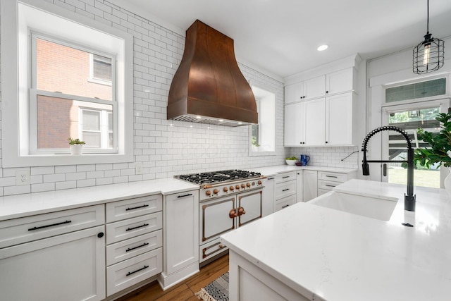 kitchen with white cabinetry, premium range hood, decorative light fixtures, and double oven range