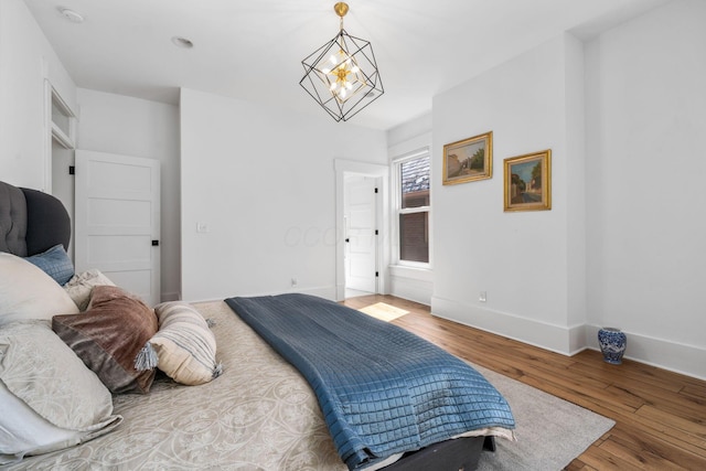 bedroom featuring an inviting chandelier and wood-type flooring